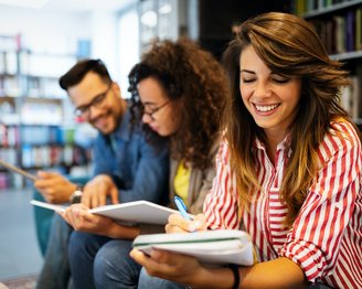 Drei Studierende sitzen nebeneinander in der Bibliothek