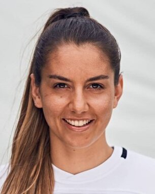 Portrait of a woman with long brown hair, smiling in a white sports jersey.