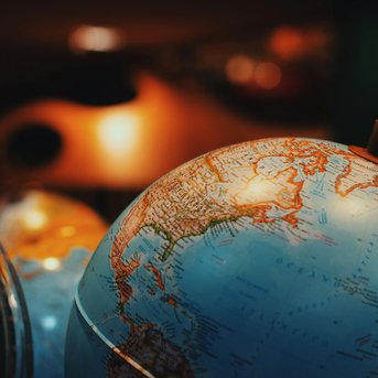 A globe displays the continents and oceans of the Earth, with a focus on Northeast Asia. The globe is partially transparent and is set against a background of blurred, colorful objects.