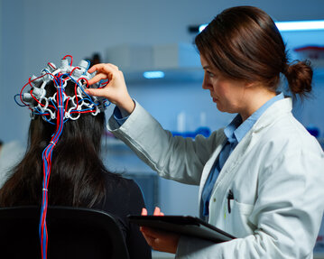 A specialist attaches electrodes to a person's scalp for a neurological examination in a laboratory.
