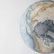 A detailed, artistic depiction of a globe showing the Arctic and surrounding landmasses. The colors are soft and earthy, with a clear compass rose in the center.