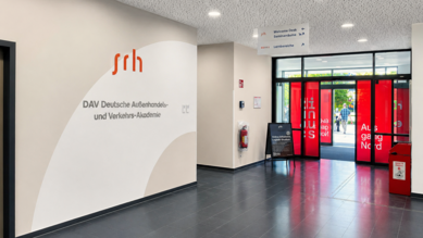 Eingangsbereich der SRH Deutsche Außenhandels- und Verkehrs-Akademie mit einem modernen Design und großen Fenstern.