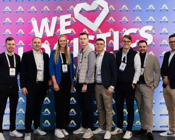 Eine Gruppe von acht Personen steht vor einem bunten Hintergrund mit dem Text "WE ♥ Analytics". Alle tragen legere Kleidung und lächeln.