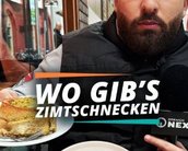 Ein Mann hält zwei Teller mit Zimtschnecken und einem anderen Gebäck, während er in die Kamera spricht. Text: "WO GIB'S ZIMTSCHNECKEN."