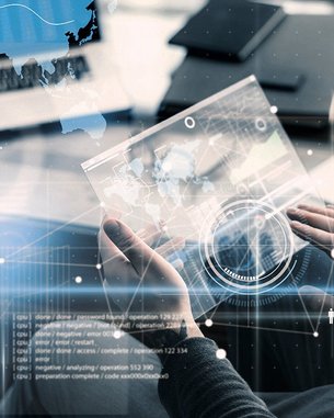 Eine Person hält ein holografisches Display mit einer Weltkarte und Datenvisualisierungen. Auf einem Tisch sind Notizbücher und ein Laptop sichtbar. Grafiken und Diagramme sind im Vordergrund eingeblendet.