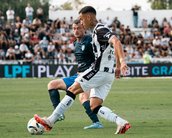 Zwei Fußballspieler kämpfen um den Ball auf dem Spielfeld, während eine Menschenmenge im Hintergrund zuschaut.