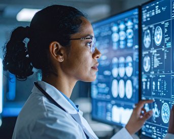 Eine Ärztin analysiert medizinische Bilddaten auf mehreren Bildschirmen, darunter Röntgenaufnahmen und MRT-Scans.