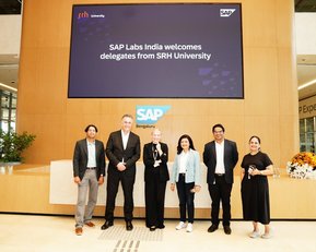 Delegates from SRH University stand in front of the reception area of SAP Labs India, surrounded by modern architecture and greenery.