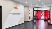 Eingangsbereich der SRH Deutsche Außenhandels- und Verkehrs-Akademie mit Beschilderung und großen Fenstern.