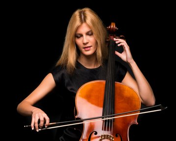 A young woman is playing the cello while intently looking at the strings. She has long blonde hair and is wearing a black top.