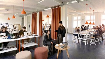 A creative workspace with several people working at tables. Some are discussing while others are working on projects or laptops.