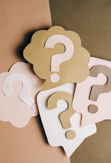 Colorful question marks in speech bubble shapes on a neutral background, arranged in various colors and sizes.