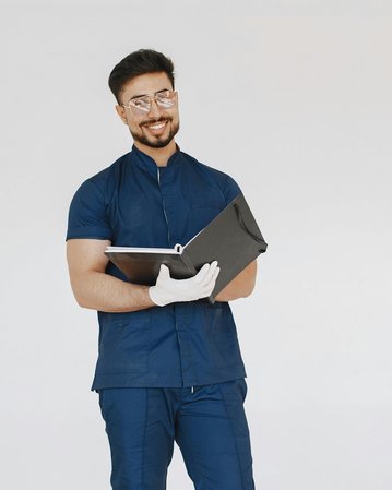 Ein lächelnder Mann in blauer Arbeitskleidung hält einen Ordner in der Hand. Er trägt eine Brille und weiße Handschuhe, während er vor einem neutralen Hintergrund steht.