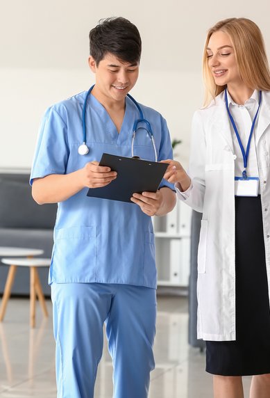 Ein männlicher Arzt in blauer Uniform und eine weibliche Ärztin in einem weißen Kittel stehen in einem modernen Raum und besprechen Unterlagen.