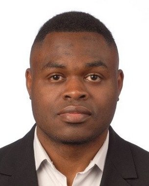 Porträt eines Mannes mit kurzem Haar, der einen schwarzen Anzug und ein helles Hemd trägt. Der Hintergrund ist neutral und hell.