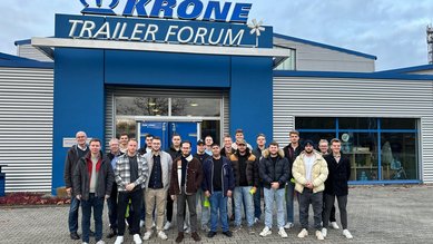 Gruppe von jungen Erwachsenen steht vor dem Krone Trailer Forum, lächelnd und in Freizeitkleidung, mit dem Gebäude im Hintergrund.