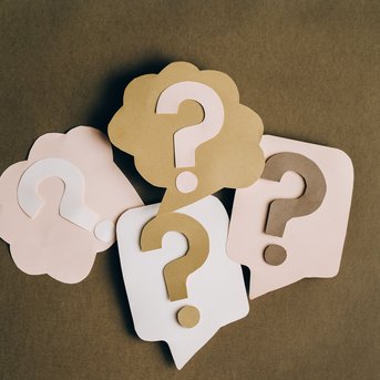 Various pastel-colored speech bubbles with question marks, indicating a discussion or uncertainty.
