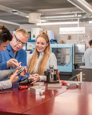 Studierende im Bereich Maschinenbau arbeiten gemeinsam mit Professor an CNC- und Spritzgussmaschinen