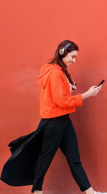 Studentin mit Handy in der Hand läuft an einer roten Wand vorbei
