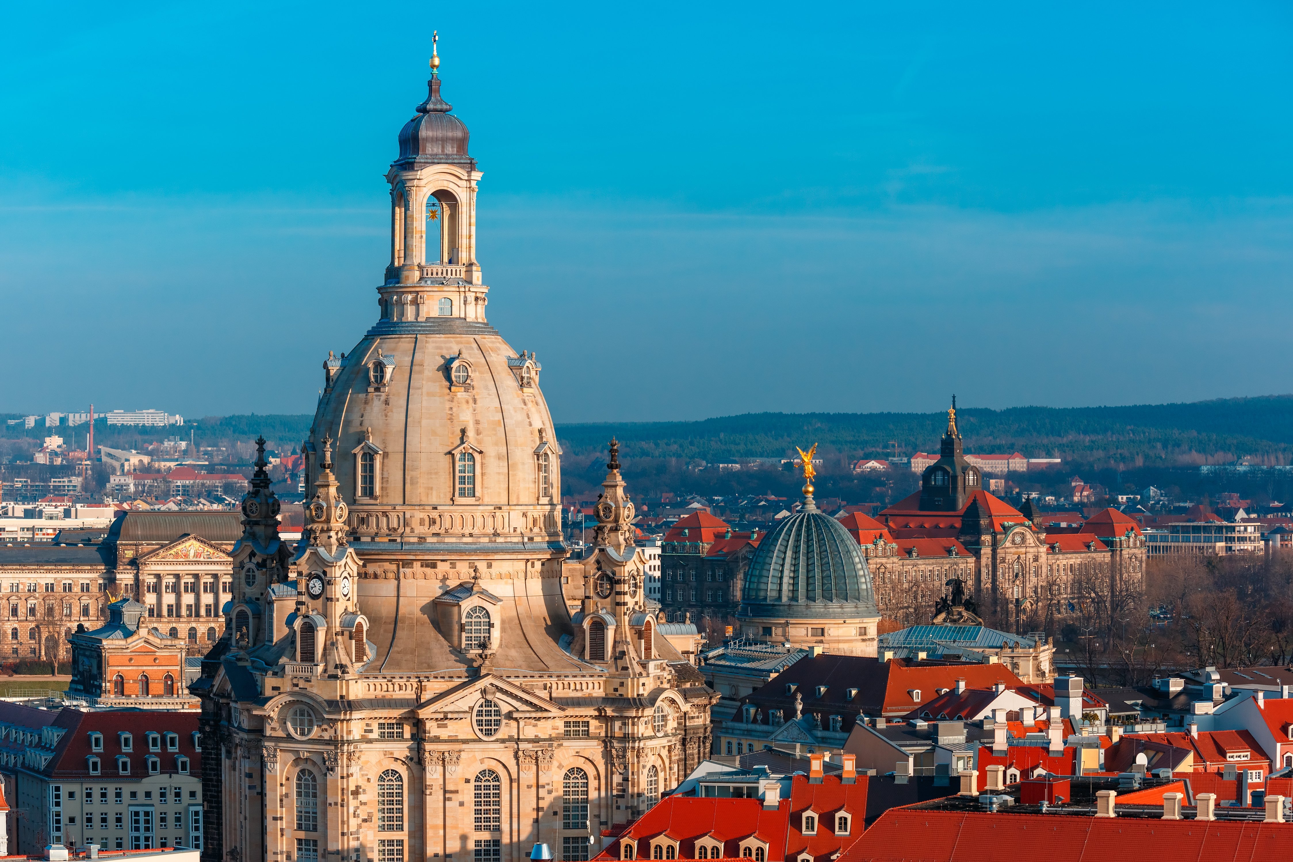 The Frauenkirche in Dresden, with its distinctive dome and baroque architecture, is surrounded by historic buildings and a clear blue sky.