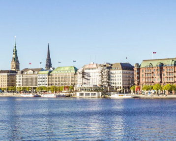 Panorama der Hamburger Altstadt am Wasser, mit historischen Gebäuden und Kirchtürmen unter klarem Himmel.
