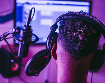 Musikproduktion_Studium_Header_Musiker_mit_Kopfhoerer In einem Musikproduktion-Studio verbringen die Studieren viel Zeit im Tonstudio