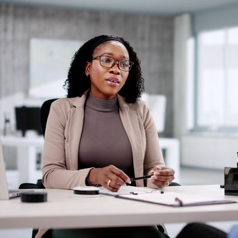 Eine Frau mit Brille spricht in einem modernen Büro mit einer anderen Person, die einen medizinischen Verband trägt.