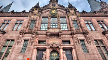Historic building with an elaborate facade, large windows, and decorative sculptures, including lion figures.