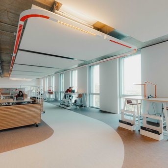 Modern office environment with large windows, flexible workspaces, and ergonomic furniture. Bright lighting and an open layout encourage collaboration.